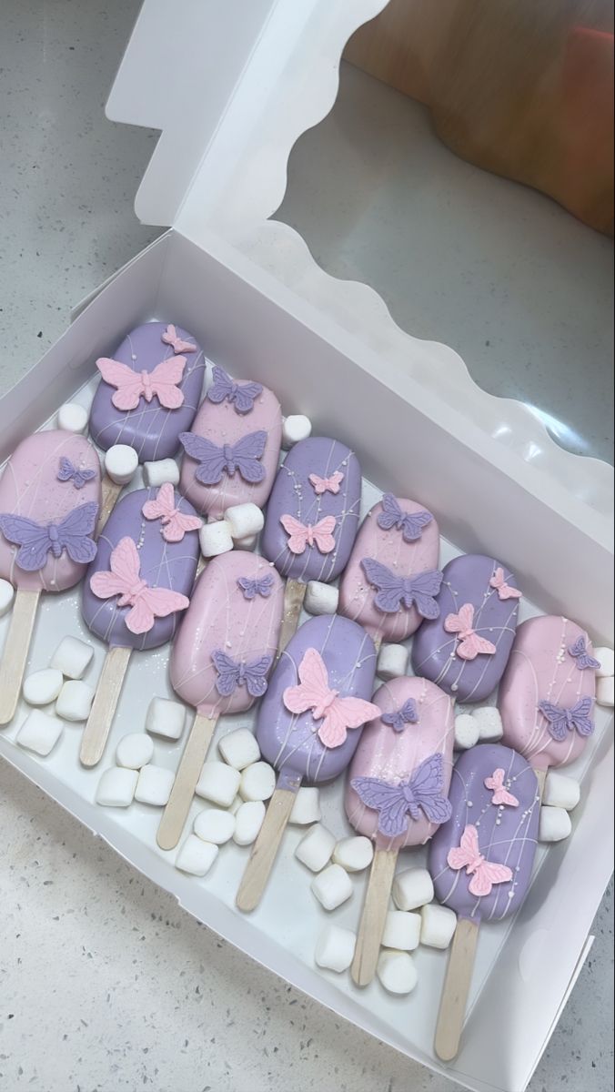 a box filled with lots of purple and white cookies on top of marshmallows