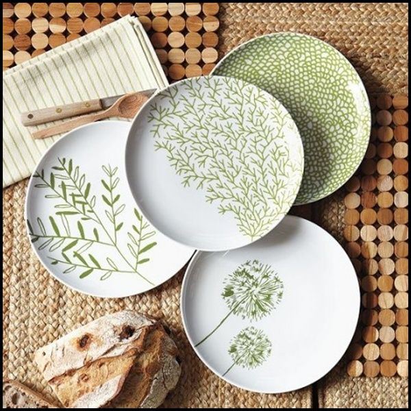 four plates with designs on them are sitting on a place mat next to bread and utensils