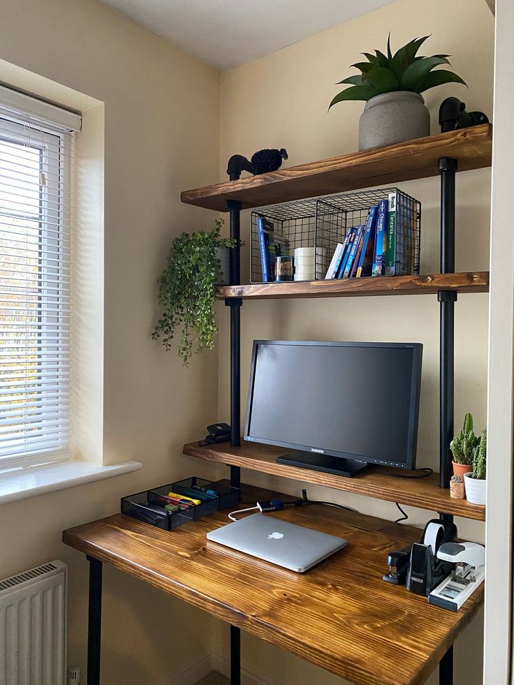 a computer desk with a laptop on top of it next to a potted plant