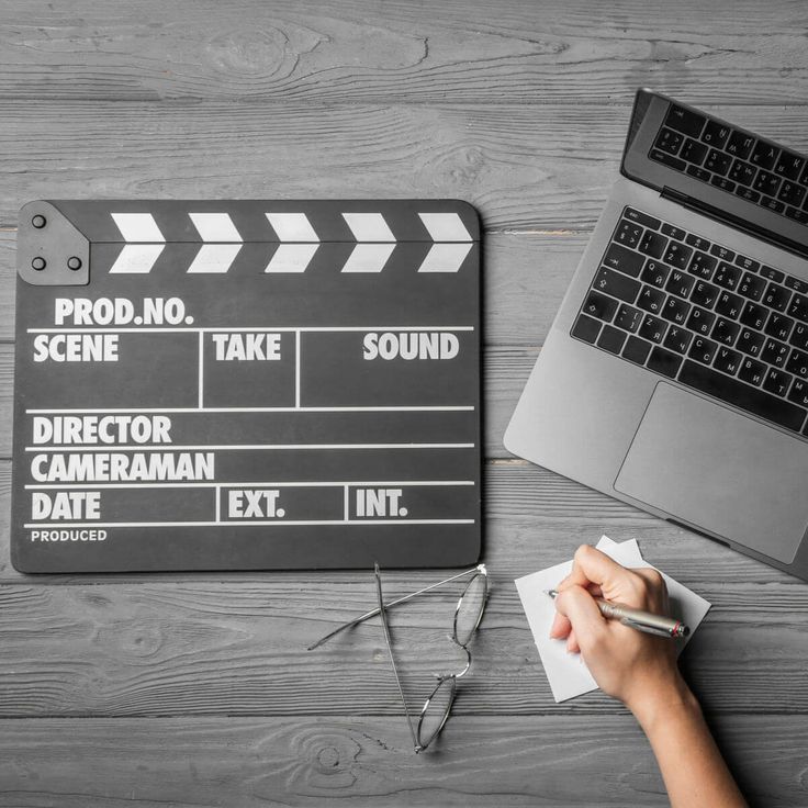 a person writing on a movie slate next to a laptop