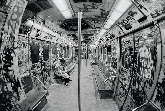 a man sitting on a bench in a subway car covered in grafitti art