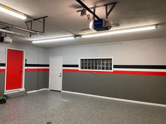 an empty room with red and grey walls, white doors and black and gray flooring