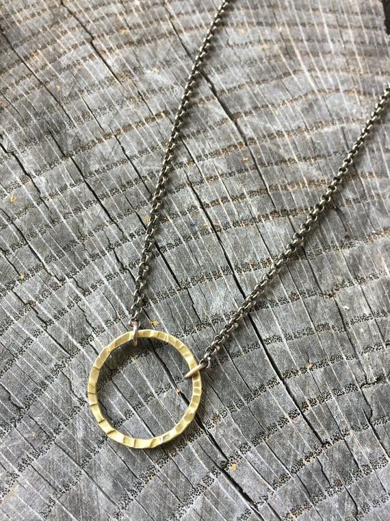 This is a neat minimalist necklace featuring a hand forged brass metalwork circle.  The black and gold pair nicely together on this simple, yet fashionable design.  Meant for guys or gals. MEASUREMENTS & SPECIFICS:PENDANT SIZE: 1"NECKLACE LENGTH: 20" FINISH: polished / lightly antiqued METAL: raw brass & blackened Stainless Steel All jewelry & wares from my studio arrive attractively packaged and ready for gifting or for keeps. All metalwork from my studio is backed by a lifetime cra Gold Minimalist Necklaces For Everyday Use, Gold Minimalist Necklace For Everyday Use, Minimalist Gold Necklace For Everyday Use, Hand Forged Minimalist Metal Jewelry, Minimalist Hand Forged Metal Jewelry, Everyday Brass Necklace, Modern Oxidized Gold Necklace, Hand Forged Circular Jewelry For Everyday Wear, Nickel Free Bronze Minimalist Jewelry