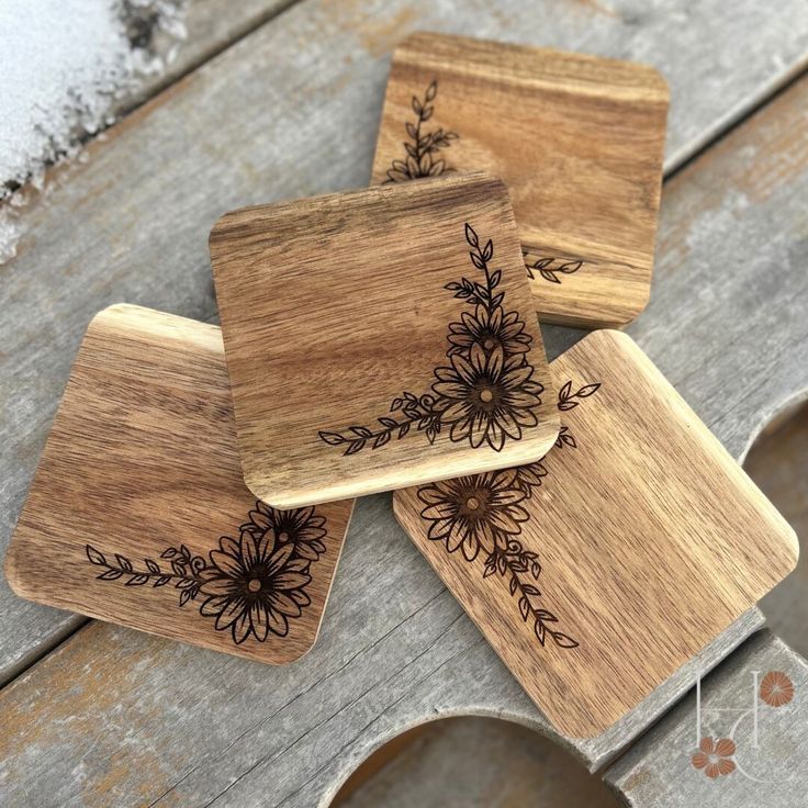 four wooden coasters with black flowers on them