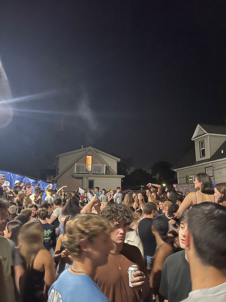 a crowd of people standing around each other at a festival or gathering in the evening