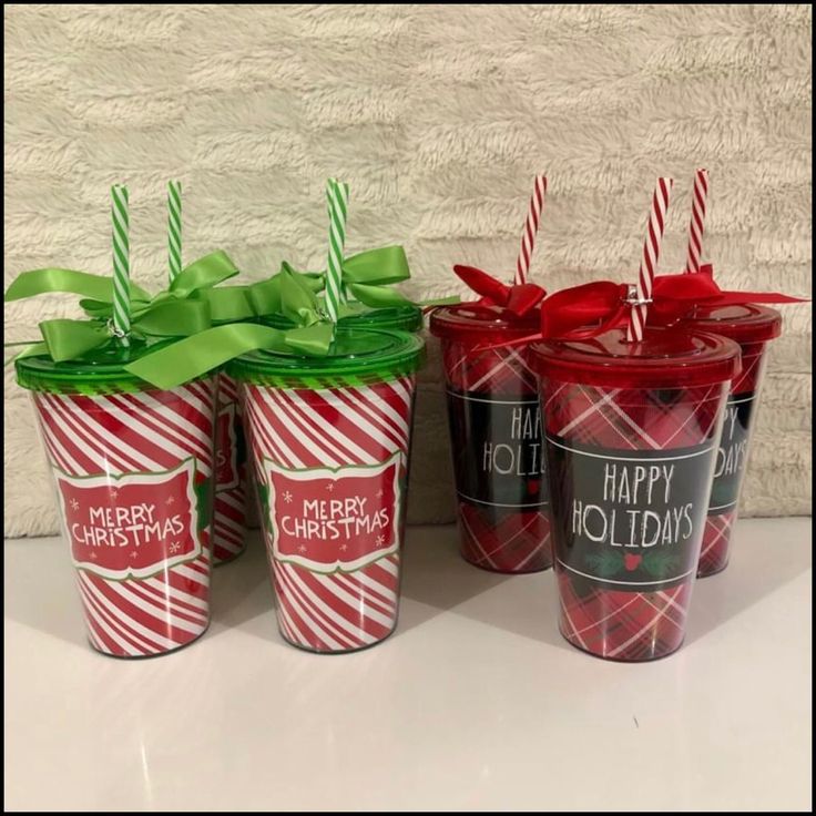 three christmas cups with candy canes and bows on them sitting next to each other