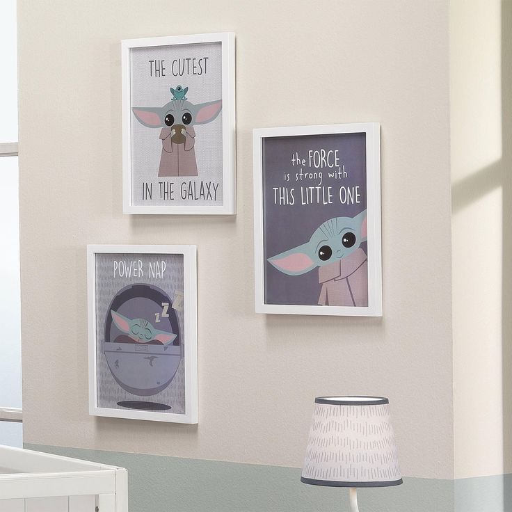 three framed pictures hang on the wall above a crib with a baby yoda lamp