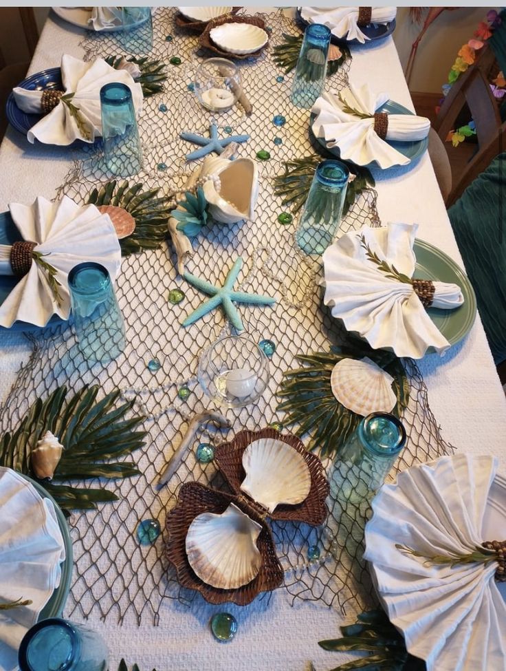 the table is set with shells, seashells and palm leaves for an ocean themed celebration