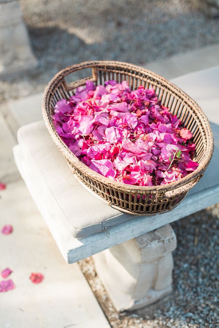 a basket filled with pink flowers sitting on top of a bench