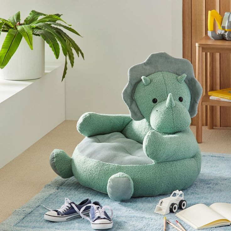 an elephant shaped chair sitting on top of a blue rug next to a potted plant