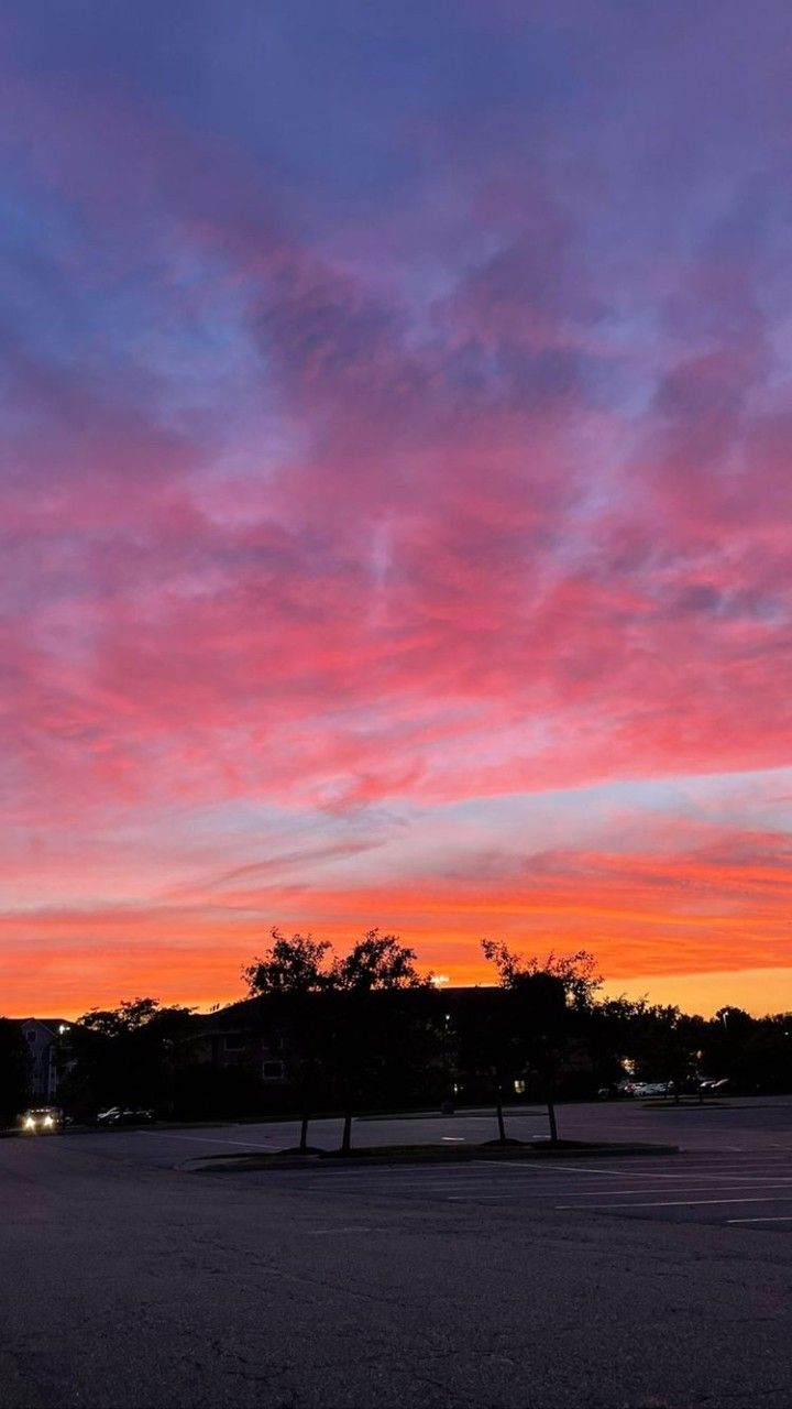 the sky is pink and blue as it sits in an empty parking lot at dusk