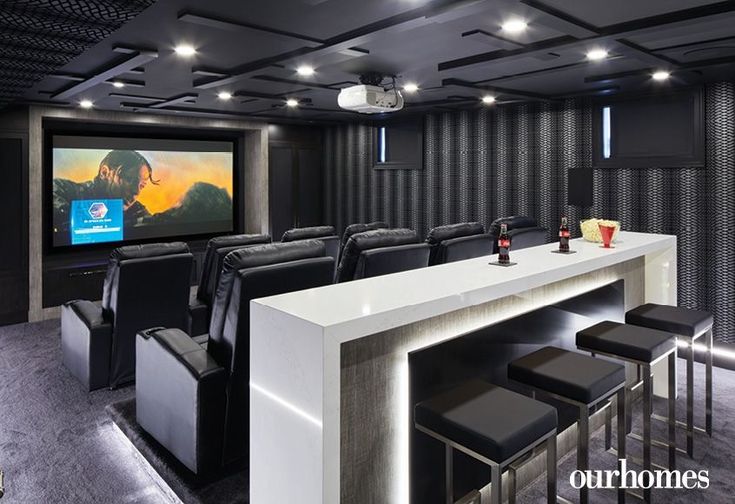 a home theater with black chairs and white counter