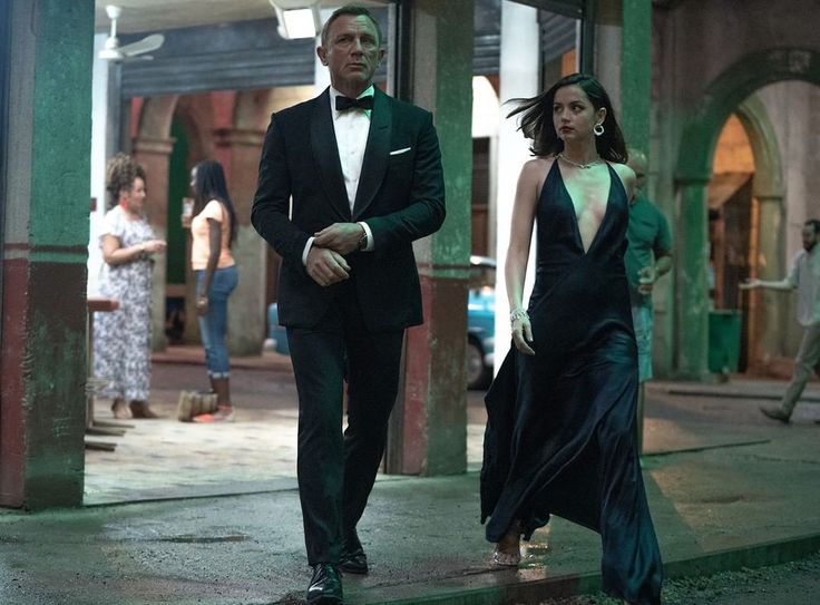 a man in a tuxedo walking next to a woman in a black dress