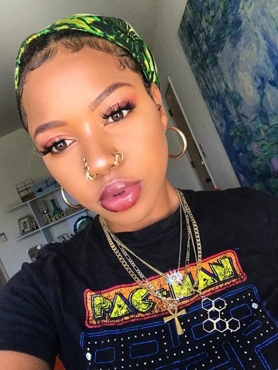 a woman with piercings on her nose wearing a black shirt and gold hoop earrings