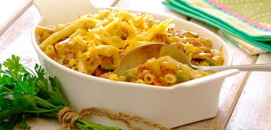 a white bowl filled with macaroni and cheese on top of a wooden table