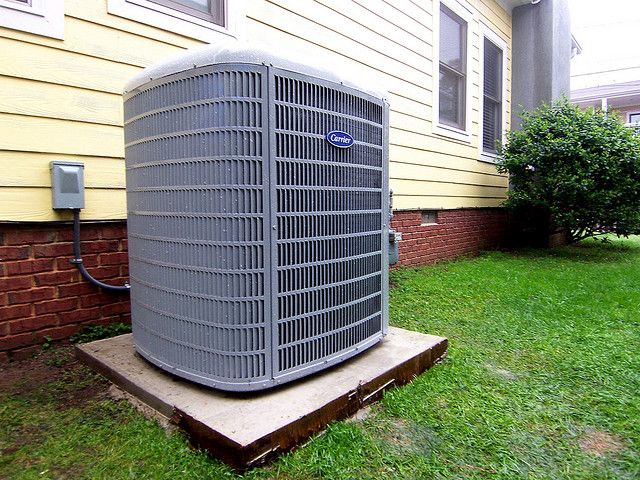 an air conditioner sitting on top of a wooden platform in front of a house