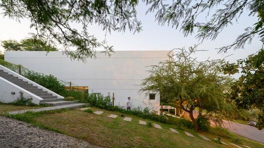 a house with stairs leading up to the roof and grass on the ground next to it