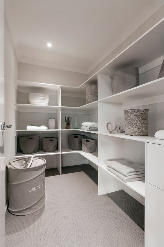 a walk in closet filled with lots of white shelves and baskets on top of them