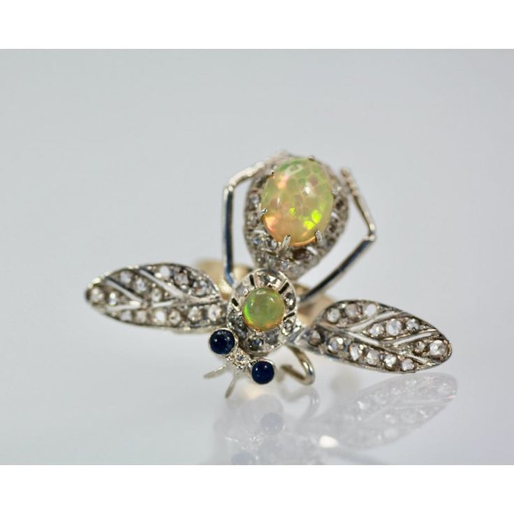 This is part of Chairish’s Fine Jewelry assortment.  14K Butterfly with Silver Articulated Wings Opal Body  This butterfly is unique as they started out as pins and I turned them into rings. The wings are set with Diamonds over silver and they move with your hand as they are flying around. The body is 14K gold and two Jelly Opals form the body and head. The eyes are Sapphire cabochons. They weigh 9.0 grams and measure 1 3/4" open wings, length is 1 1/4" and the depth is 6.01 average ring size 6. Antique White Gold Brooches With Rose Cut Diamonds, Collectible Hallmarked Pendant Brooch, Collectible Hallmarked Pendant Brooches, Collectible Round Gemstone Brooch, Collectible Round Gemstone Brooches, Fine Jewelry White Gold Brooches With Gemstones, White Gold Gemstone Brooches Fine Jewelry, White Gold Gemstone Brooch Fine Jewelry, White Gold Gemstone Brooch In Fine Jewelry Style