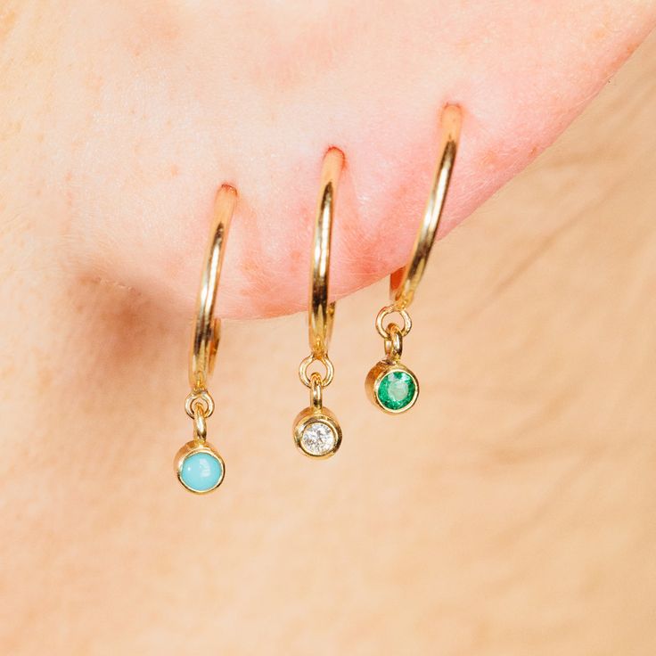 14k gold tiny huggie hoop earrings with bezel set round emeralds dangling from the bottom SPECIFICS • hoops are approx. 10mm• emerald stones are approx. 2mm each• sold as pair or single Stackable Huggie Earrings Fine Jewelry For Gift, Stackable Huggie Earrings As Gift In Fine Jewelry, Yellow Gold Sterling Silver Huggie Earrings With Birthstone, Fine Jewelry Emerald Huggie Earrings, Everyday Jewelry With Bezel Setting For May Birthstone, Green Dainty Huggie Jewelry, Dainty Green Huggie Jewelry, Dainty Sterling Silver Huggie Earrings With Birthstone, Dainty Sterling Silver Birthstone Huggie Earrings