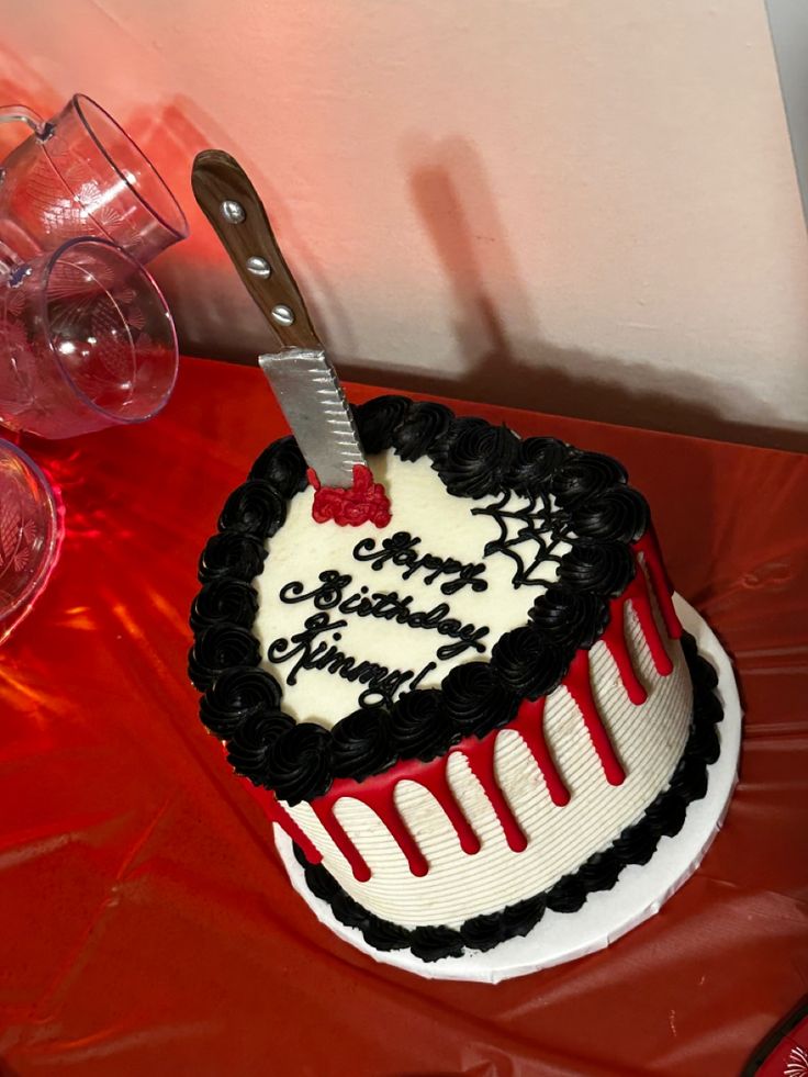 a heart shaped cake with a knife sticking out of it on top of a table