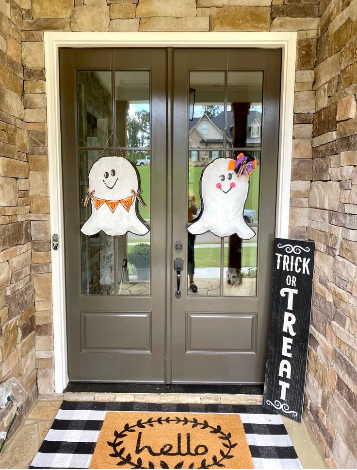 two halloween decorations on the front door of a house with black and white checkered rug