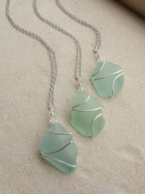 two green necklaces sitting on top of a white table next to a window sill