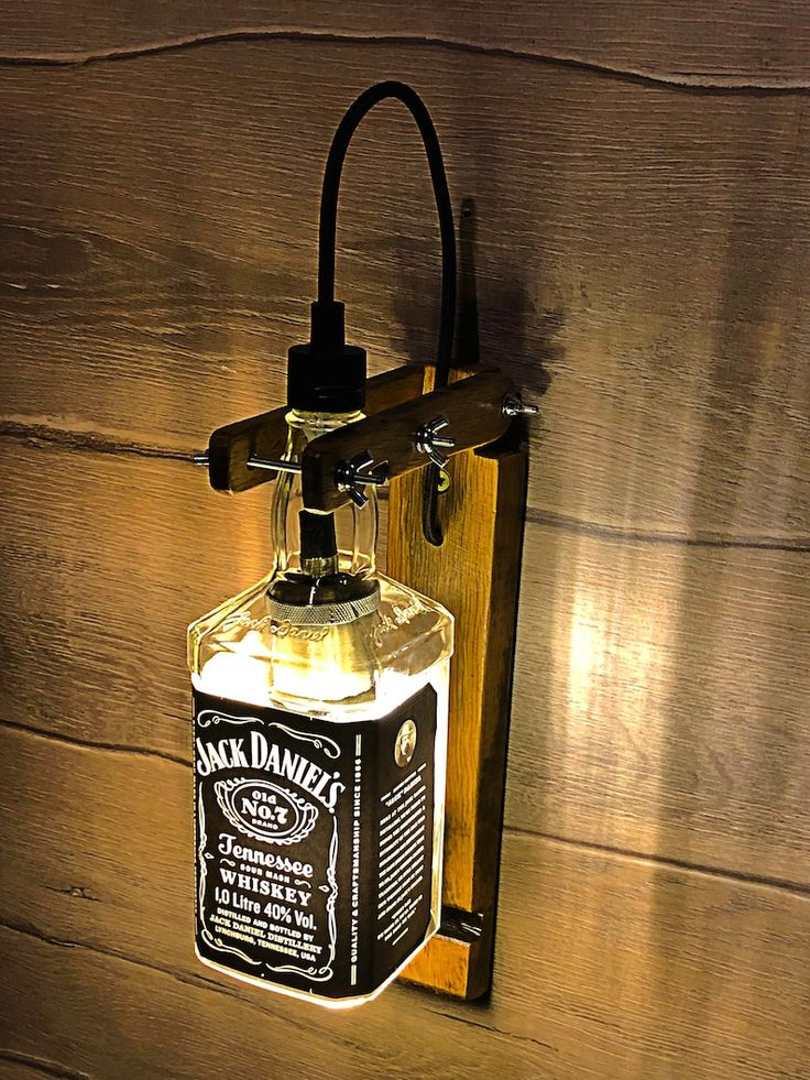 a light that is on the side of a wooden wall with a bottle hanging from it