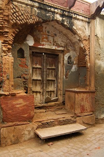 an old building with a wooden door and some steps leading up to the outside area