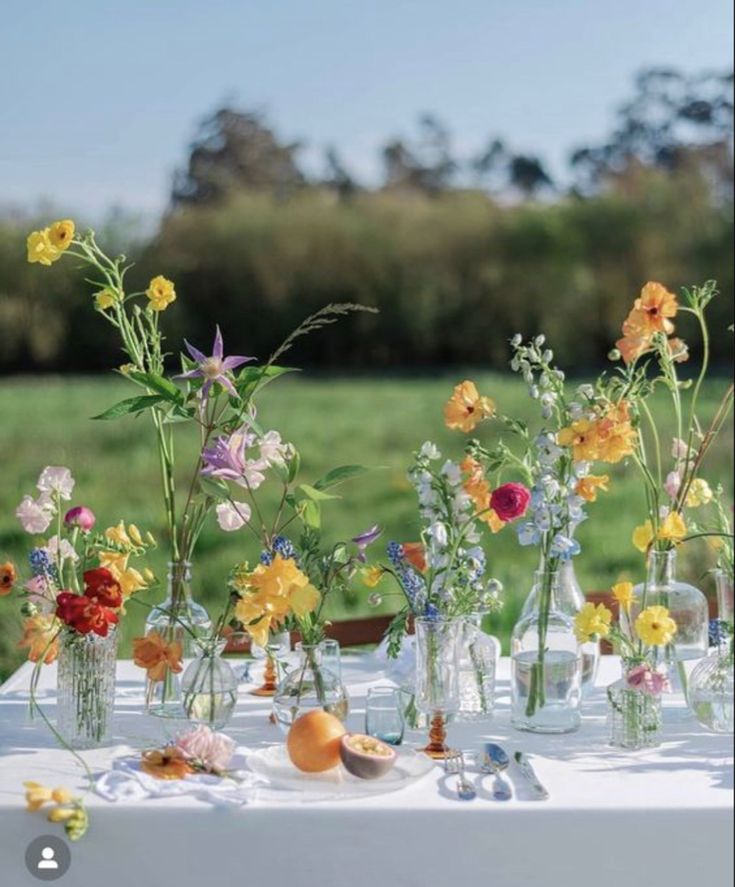 a table topped with lots of vases filled with different types of flowers and plants