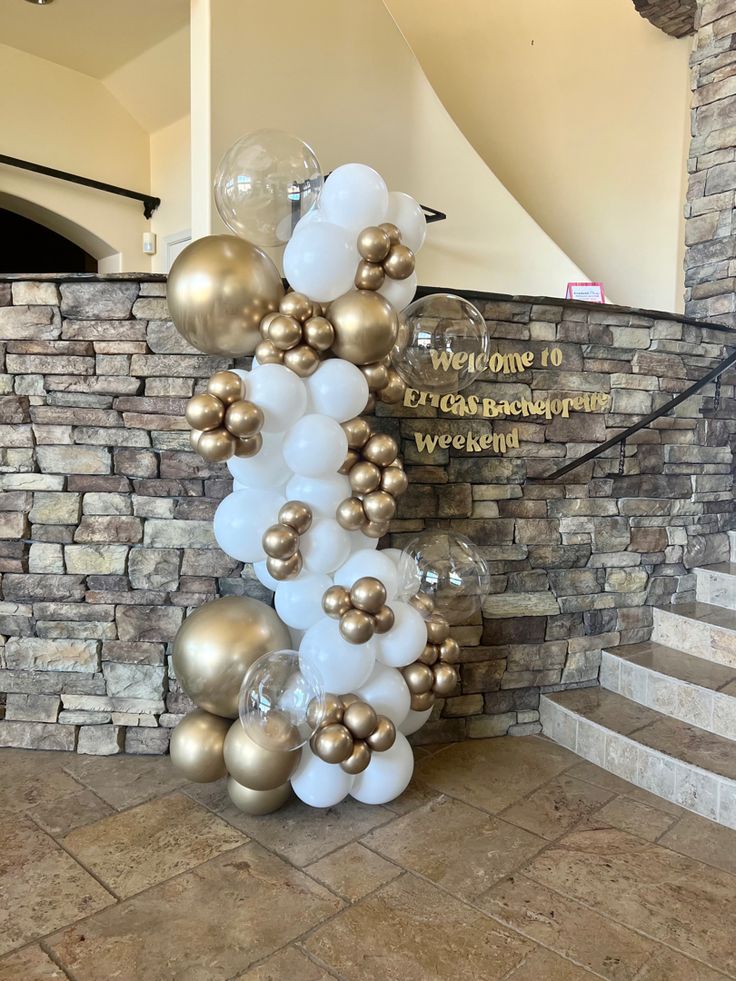 a bunch of balloons sitting on top of a floor next to a brick wall and stairs