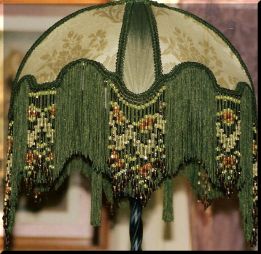 a green lamp shade with beaded fringes and beads hanging from it's side