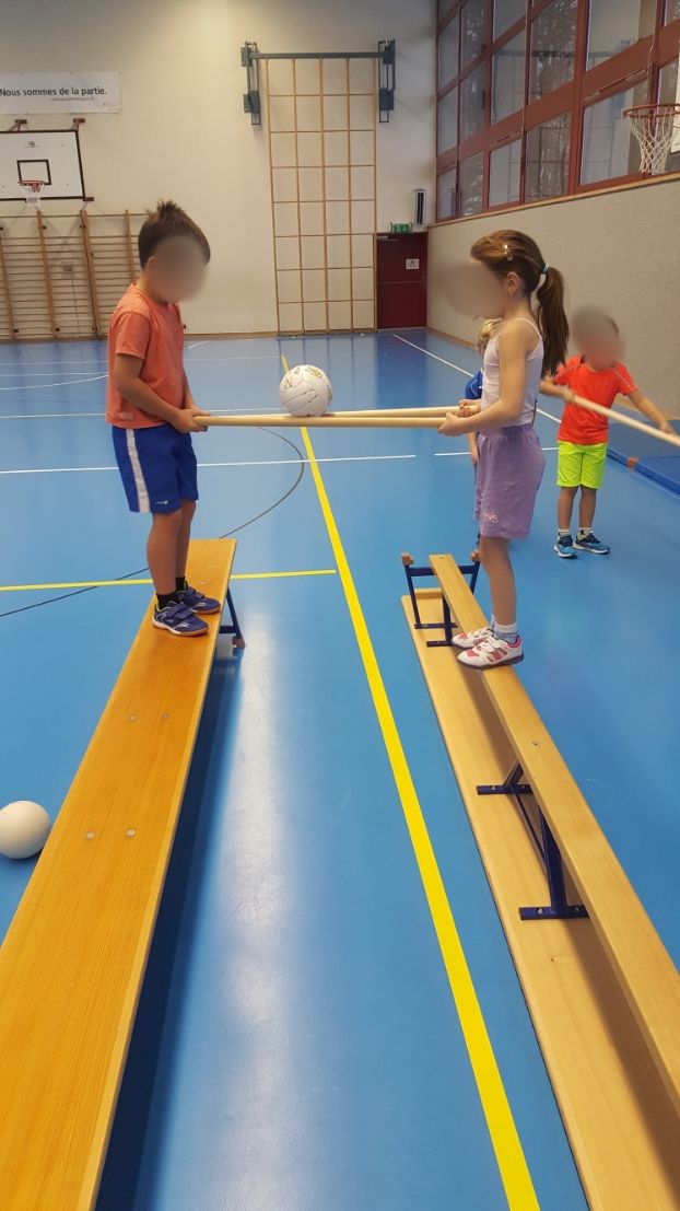 two young children playing with a ball in an indoor gym