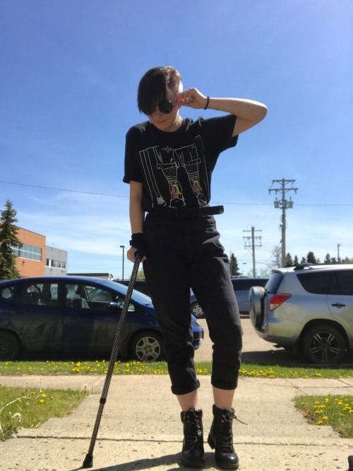 a woman standing on the sidewalk with her head in her hands and holding a cane