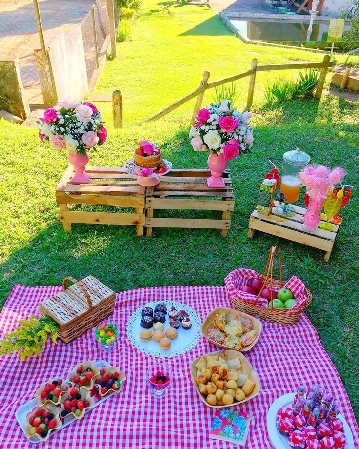 an outdoor picnic is set up on the grass with pink flowers and plates of food