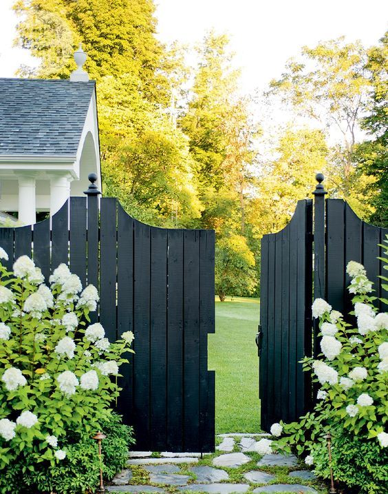 an open black gate with white flowers in the foreground