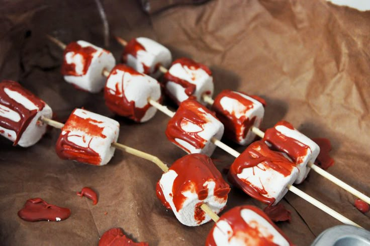 marshmallows covered in red and white icing sitting on top of brown paper