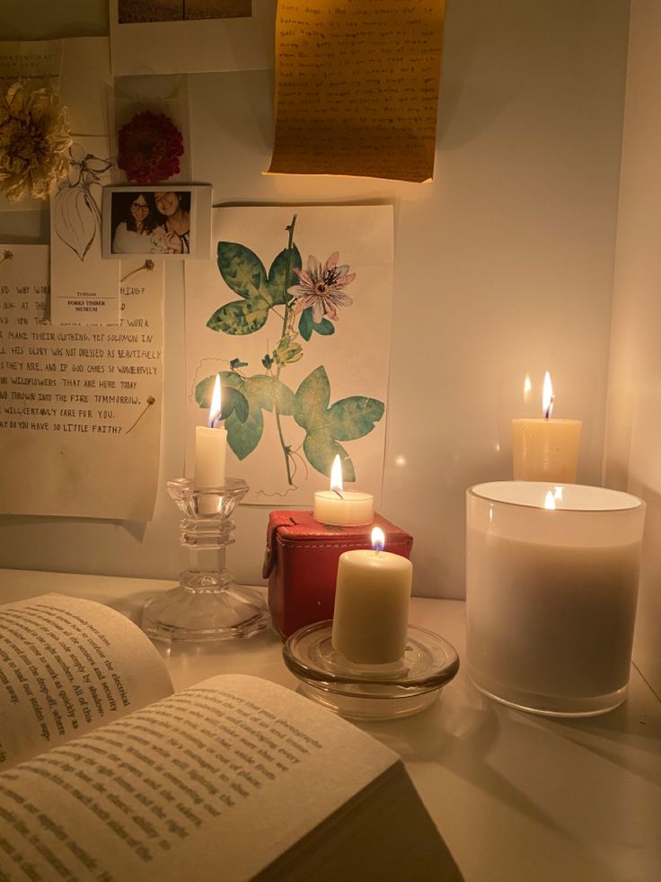 two lit candles sit on a table next to an open book