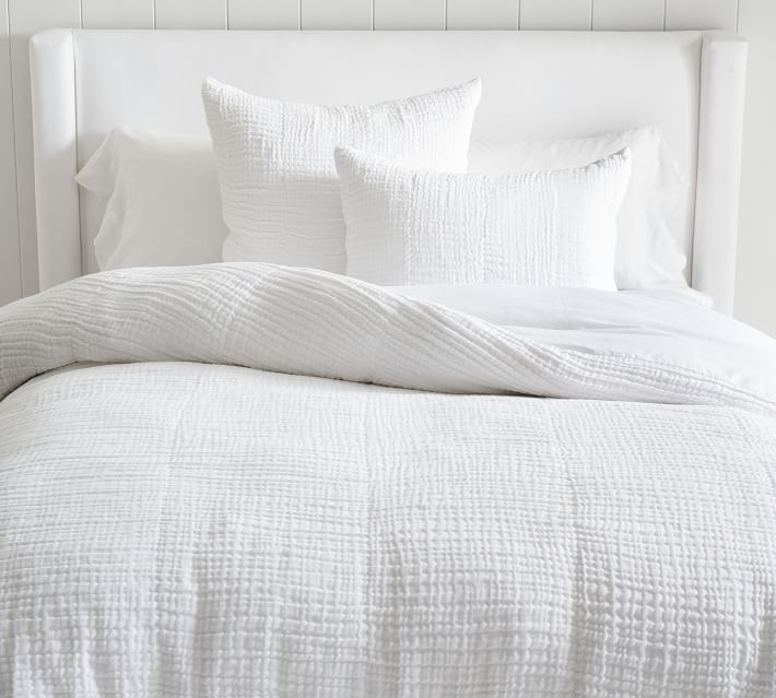 a bed with white sheets and pillows on it