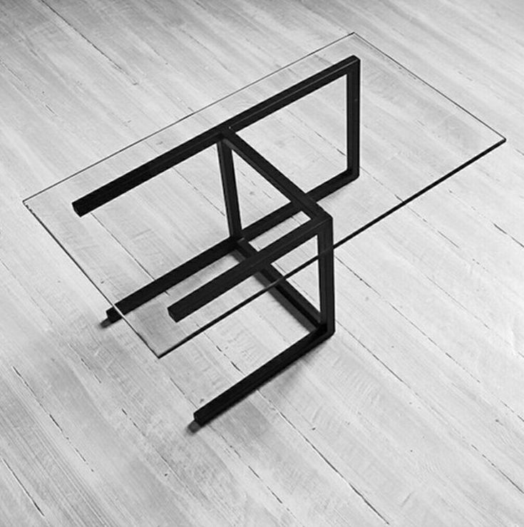 a black and white photo of an upside down glass table on the floor with one leg in the air