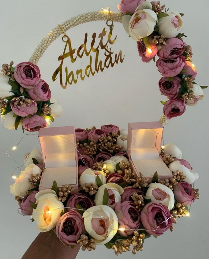 a person holding up a ring with flowers on it and the words adir haddah written in gold