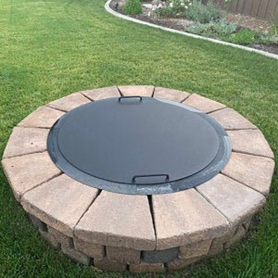 a fire pit sitting on top of a lush green field