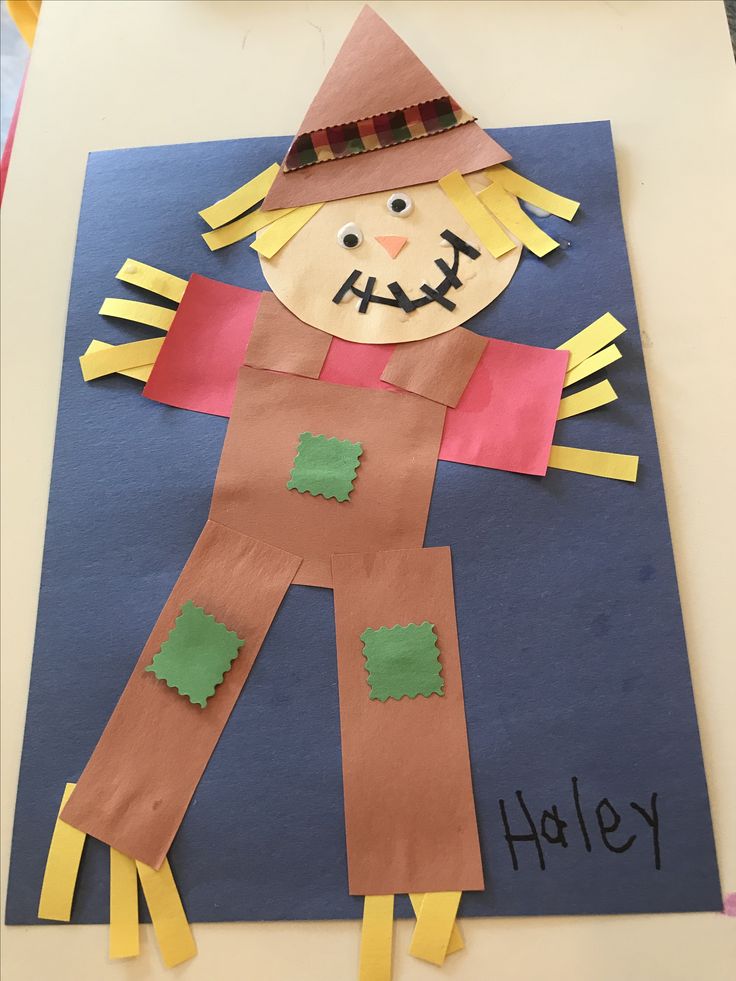 a paper scarecrow made out of construction paper on a blue background with the words happy written below it