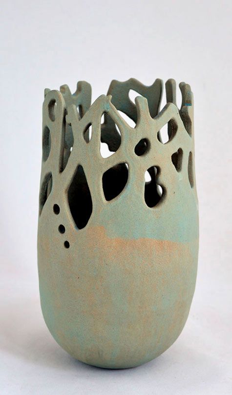 a ceramic vase with holes in it on a white background