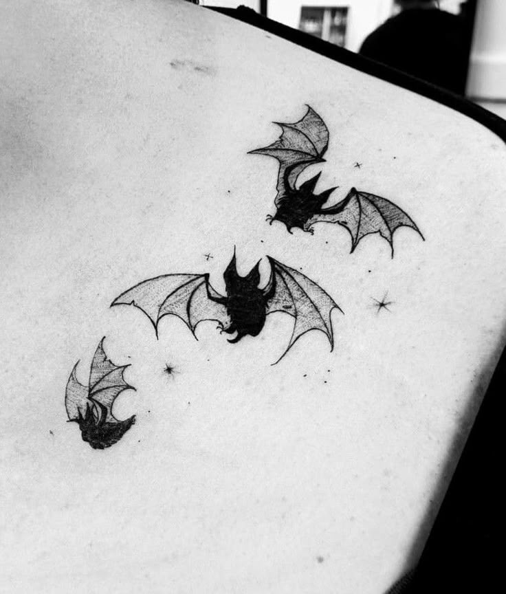 three bats on the back of a woman's upper body, with their wings spread out