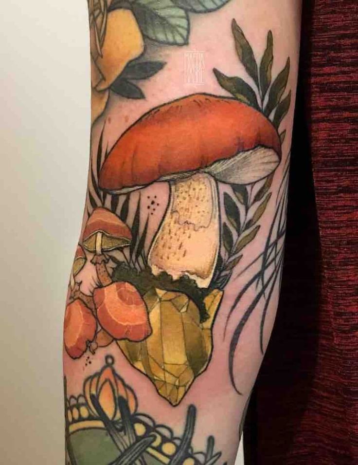 a woman's arm with tattoos on it and an image of mushrooms in the background