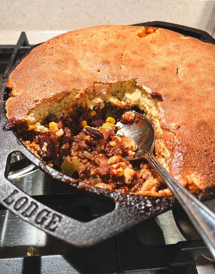 a skillet filled with food sitting on top of a stove next to a spatula