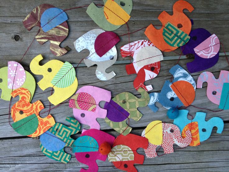 an assortment of colorful felt elephants hanging from strings on a wooden surface with string attached to them