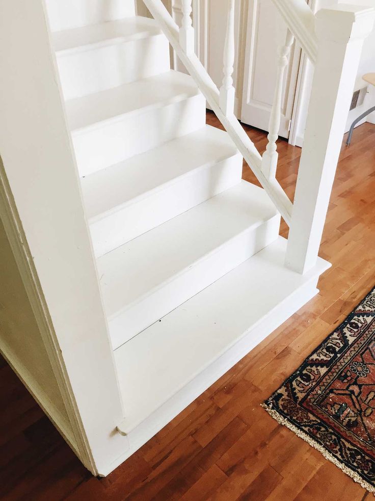 there is a rug on the floor next to some white staircases and railings