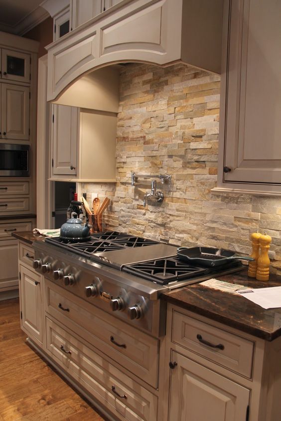 a stove top oven sitting inside of a kitchen next to wooden flooring and cabinets